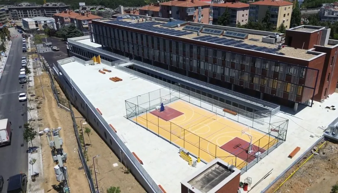 Bina ve çatıdaki turuncu-kırmızı basketbol sahasının yakından havadan görünümü