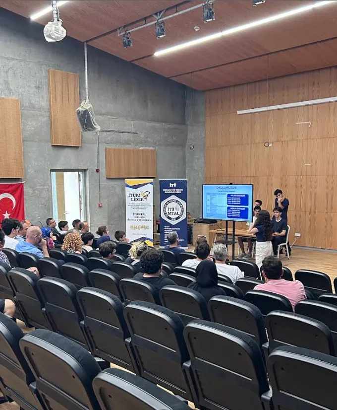 Konferans salonunda ziyaretçilere okulu tanıtan öğrenciler